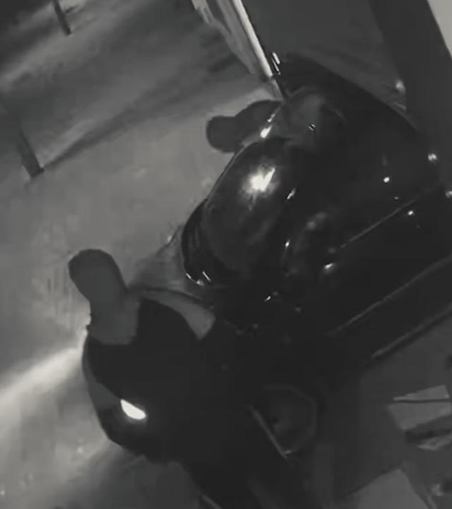 Das Bild zeigt eine Aufnahme einer Überwachungskamera, auf der ein Auto rückwärts in eine Ladenfront gefahren ist.