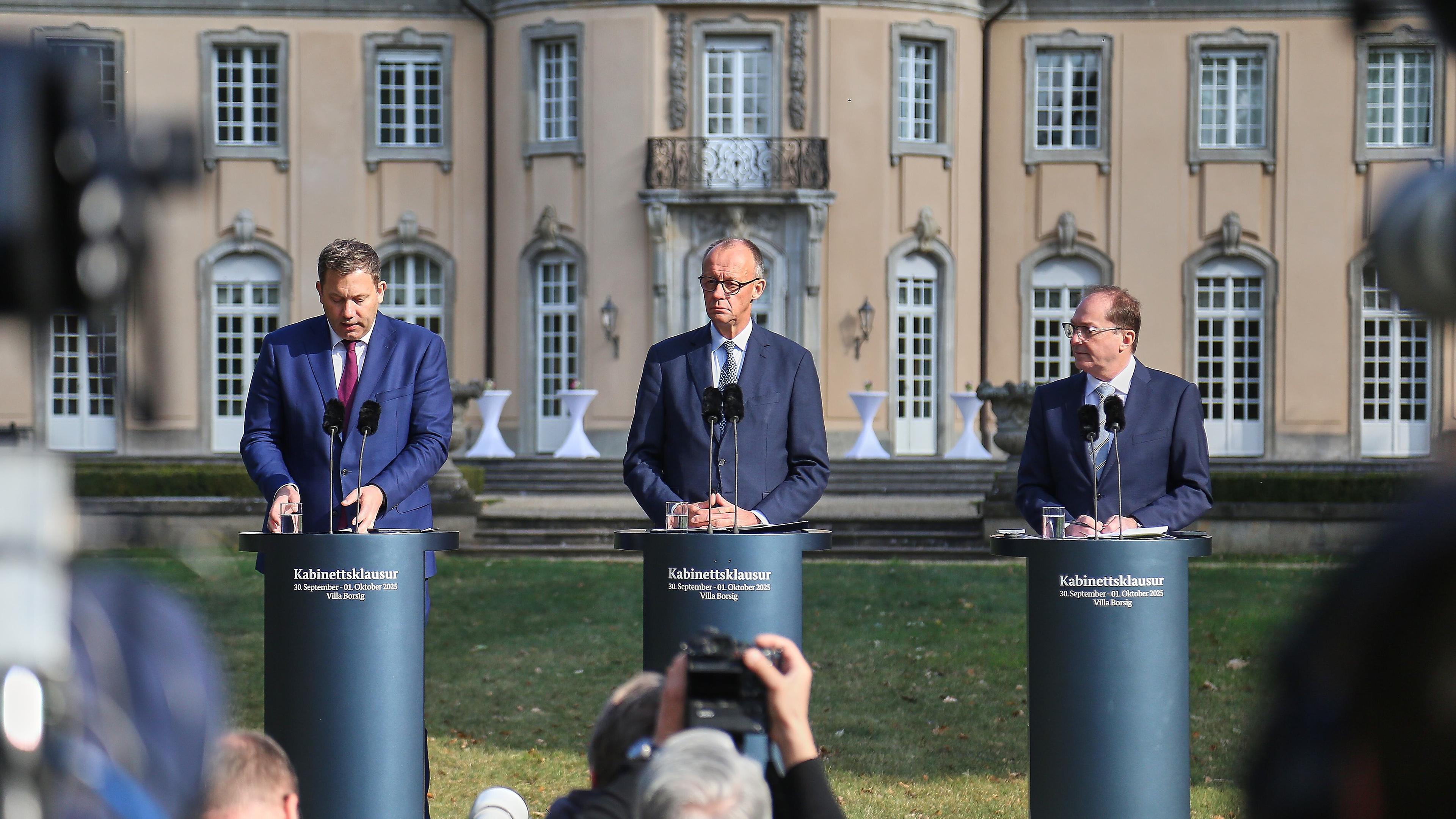 Auf dem Bild sind sind Bundesinnenminister Alexander Dobrindt, Bundeskanzler Friedrich Merz und Bundesminister der Inneren Lars Klingbeil zu sehen. Sie befinden sich zu dritt als Sprecher auf einer Pressekonferenz bezüglich der Kabinettsklausur.