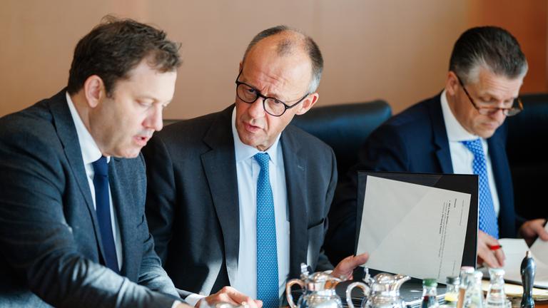Archiv: Der deutsche Finanzminister Lars Klingbeil (l) und Bundeskanzler Friedrich Merz (2vl) unterhalten sich neben dem Chef des Bundeskanzleramts, Thorsten Frei (rechts), während einer Kabinettssitzung in Berlin am 5. 11. 2025. 