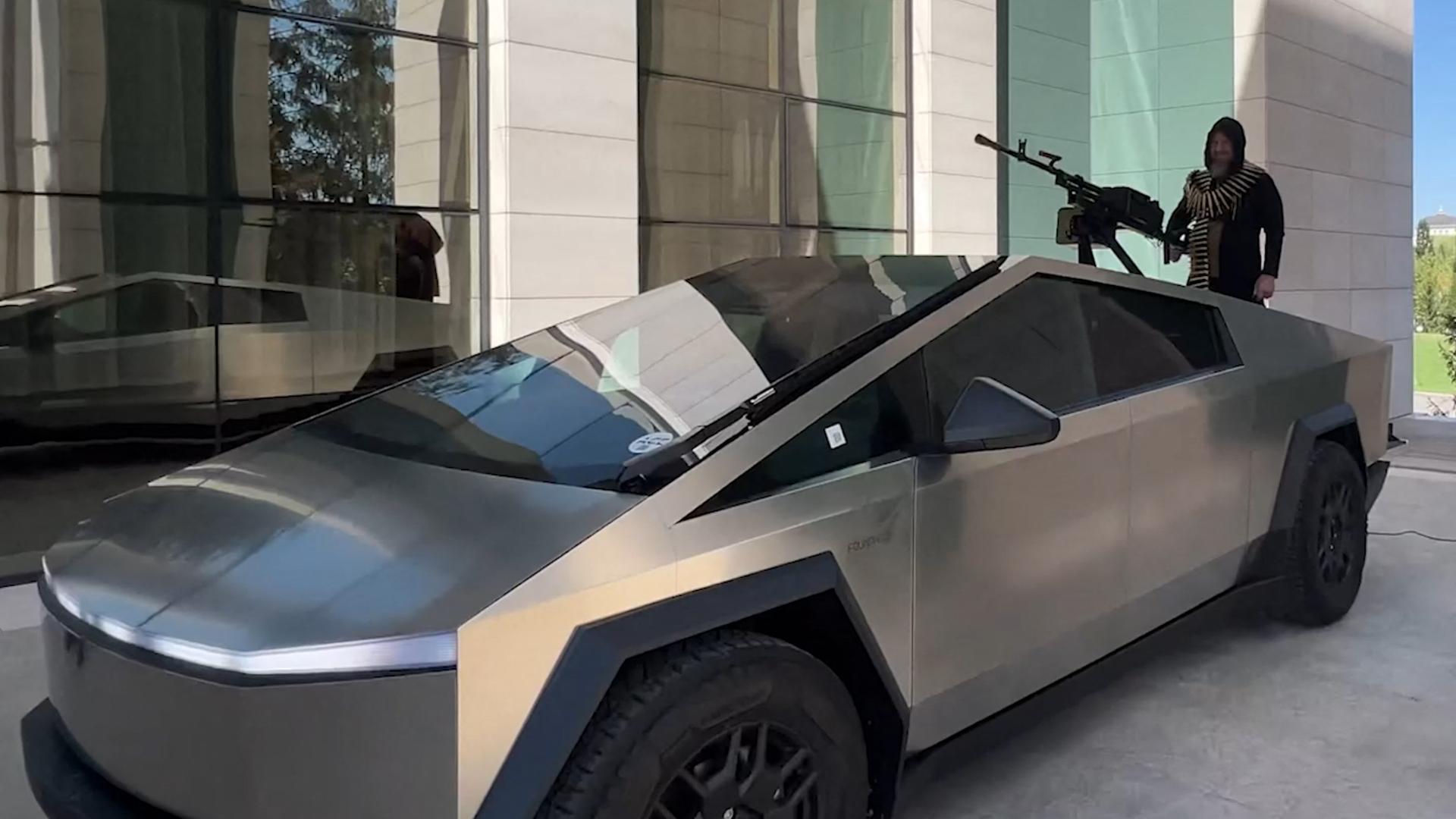 Der tschetschenische Machthaber Kadyrow steht auf einem Cybertruck der Marke Tesla. Vor ihm ist ein schweres Maschinengewehr auf dem Wagen montiert.