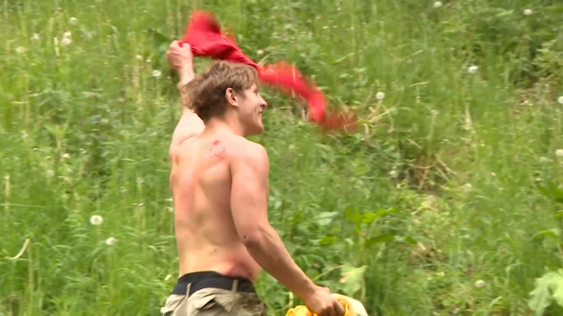 Der deutsche Tom Kopke jubelt nach dem Sieg im jährlichen "Cheese Rolling Contest" in dem er sein rotes T-Shirt über seinen Kopf schwenkt.