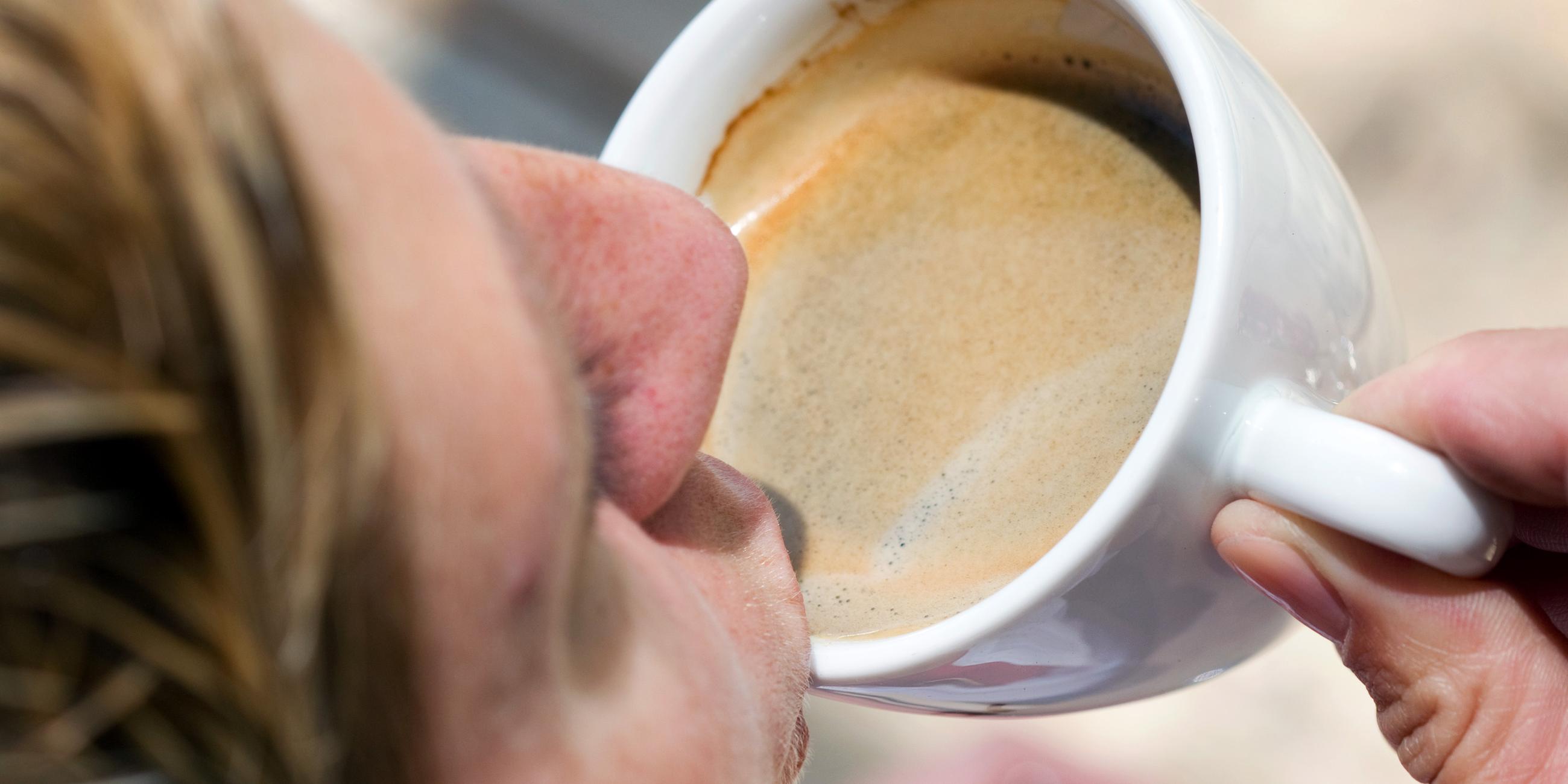 Eine Frau trinkt einen schwarzen Kaffee.