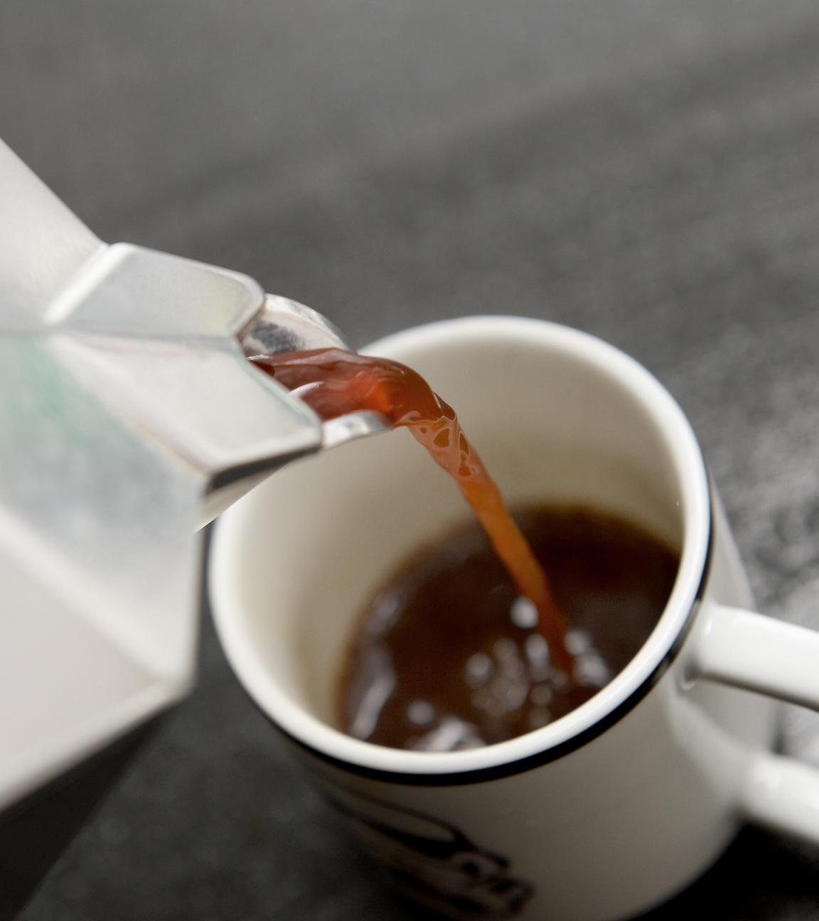 eine tasse wird mit kaffee gefuellt