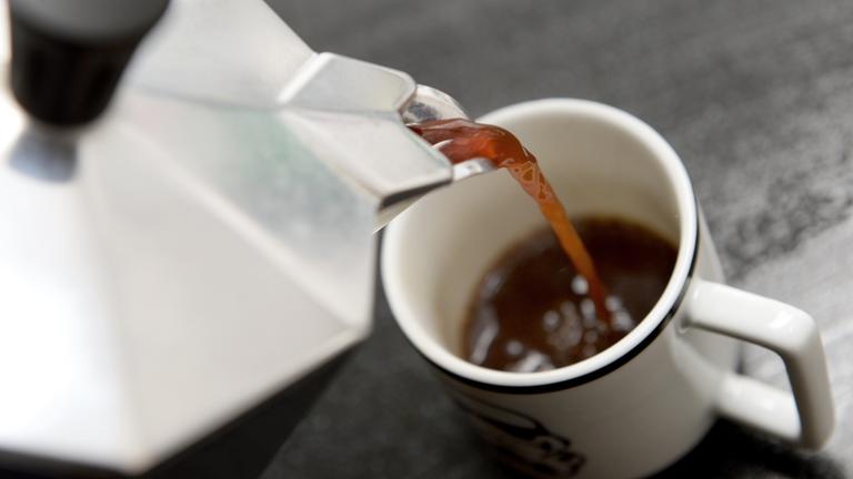 eine tasse wird mit kaffee gefuellt