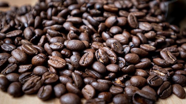 Berlin: Geröstete Kaffeebohnen liegen auf einem Tisch.