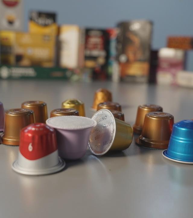 Kaffeekapseln verschiedener Marken liegen gesammelt auf einem Tisch