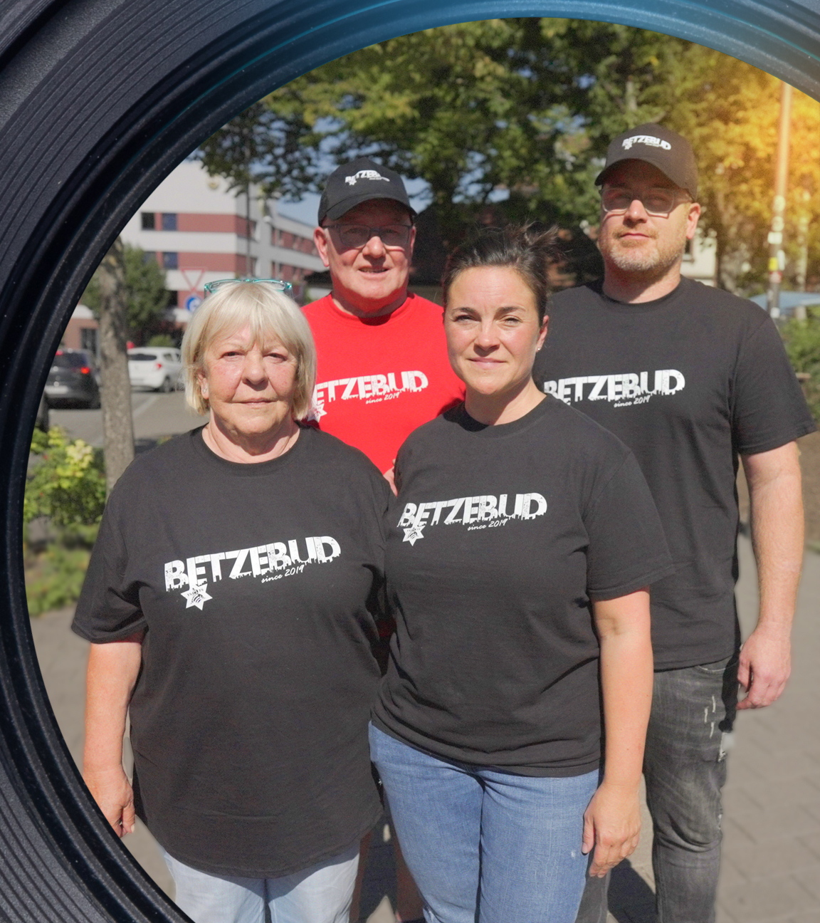 Helga Reitmayer, Armin Kraus, Sandy Kraus, Armin Kraus jr. stehen eng beieinander. Die zwei Männer tragen Mützen. Alle vier tragen T-Shirts mit der Aufschrift "Betzebud".