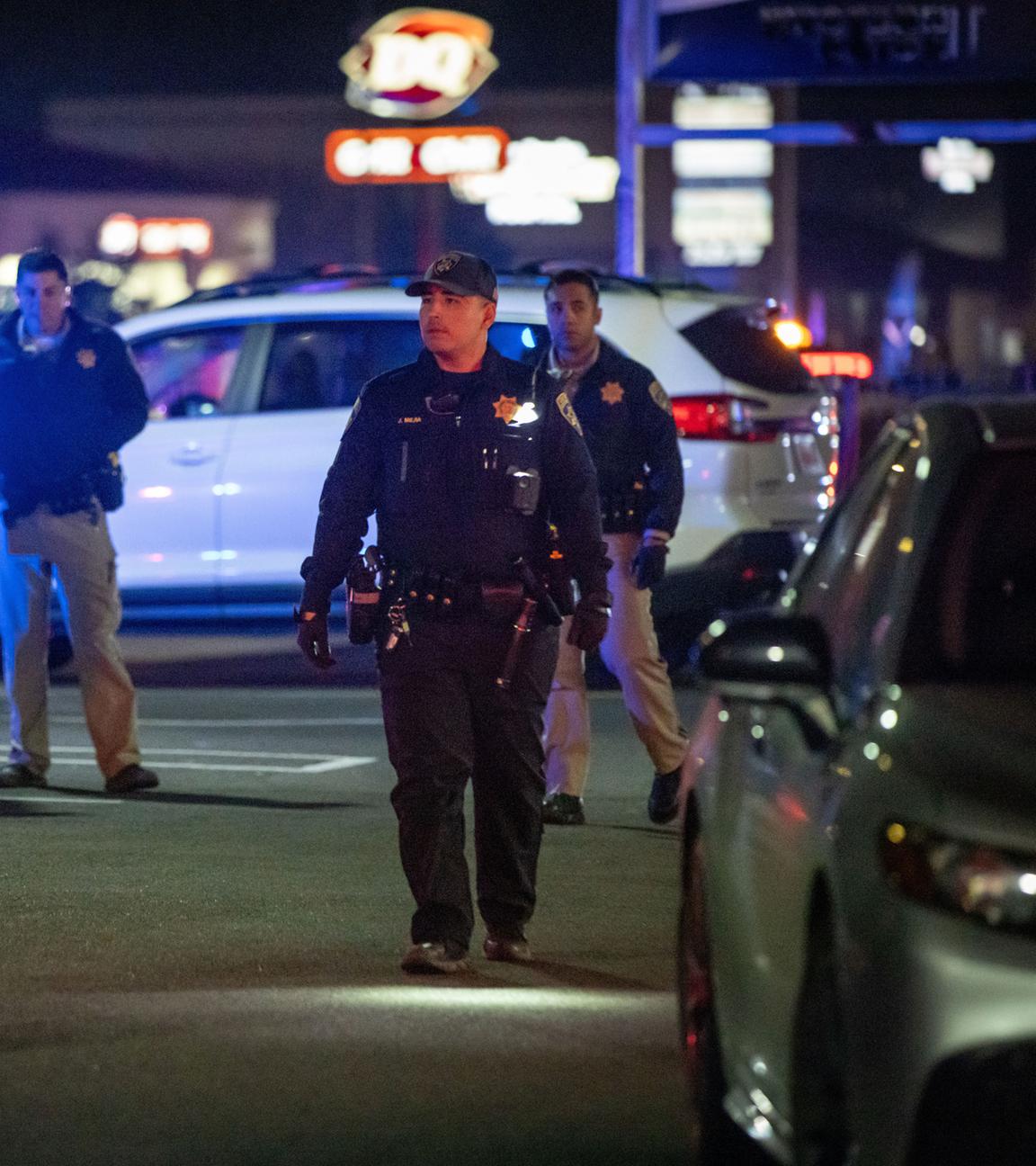 Einsatzkräfte gehen über einen Parkplatz in der Nähe eines Tatorts, nachdem Schüsse in Stockton gefallen waren. 
