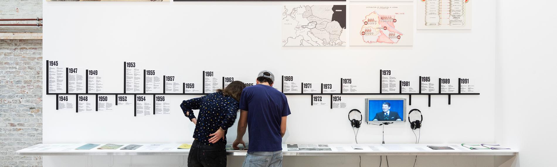 Zwei Personen vor einer Ausstellungswand.