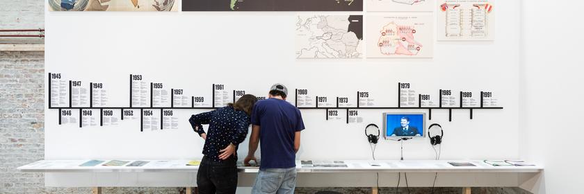 Zwei Personen vor einer Ausstellungswand.