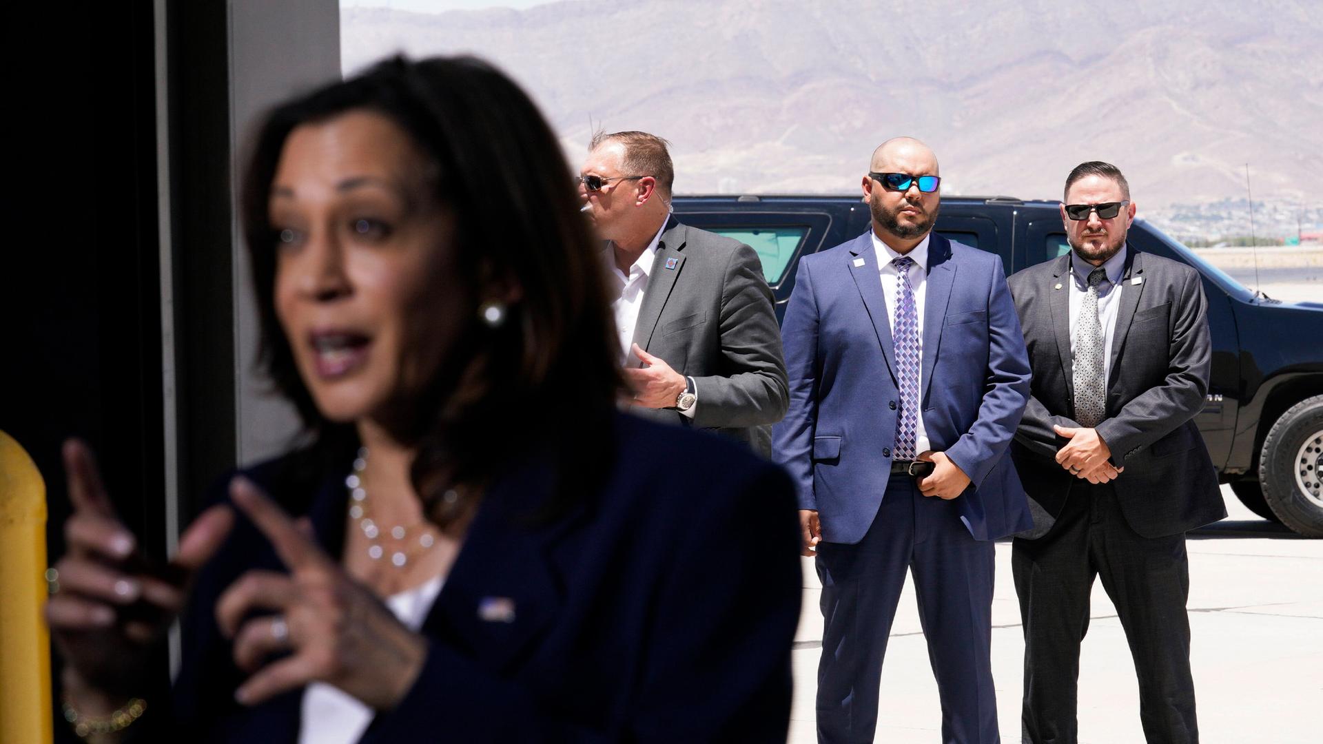 25.06.2021, El Paso, USA: US-Vizepräsidentin Kamala Harris spricht nach einem Besuch der Grenze am Flughafen El Paso – Secret-Service-Agenten sichern sie im Hintergrund.