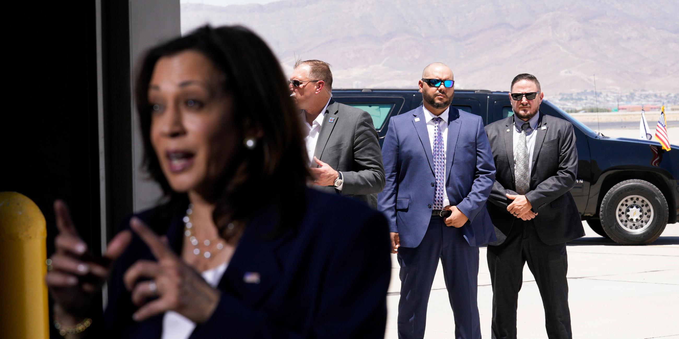 25.06.2021, El Paso, USA: US-Vizepräsidentin Kamala Harris spricht nach einem Besuch der Grenze am Flughafen El Paso – Secret-Service-Agenten sichern sie im Hintergrund.