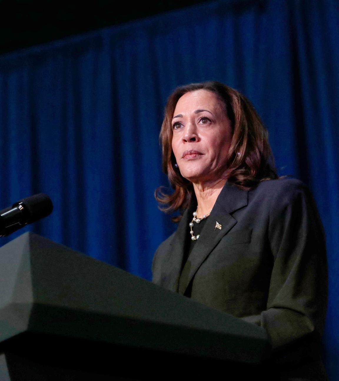 Vizepräsidentin Kamala Harris steht in einem dunklen Anzug vor einem dunkelblauen Hintergrund und schaut ernst in die Kamera.