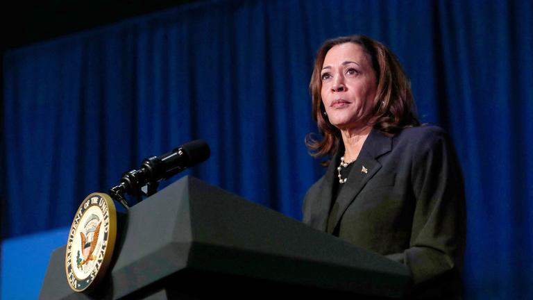 Vizepräsidentin Kamala Harris steht in einem dunklen Anzug vor einem dunkelblauen Hintergrund und schaut ernst in die Kamera.