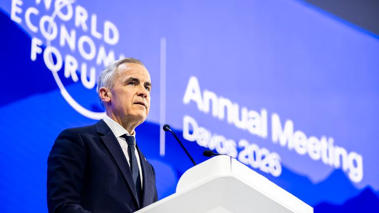 Mark Carney steht hinter einem Rednerpult vor blauem Hintergrund, auf dem "World Economic Forum" steht.
