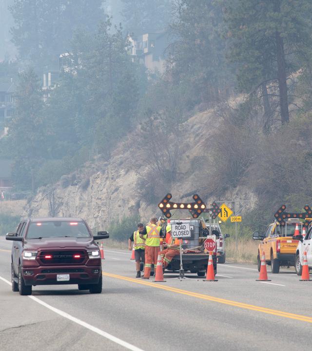 Waldbrände in British Columbia: Ein Einsatzfahrzeug fährt an einer gesperrten Strecke des Highway vorbei