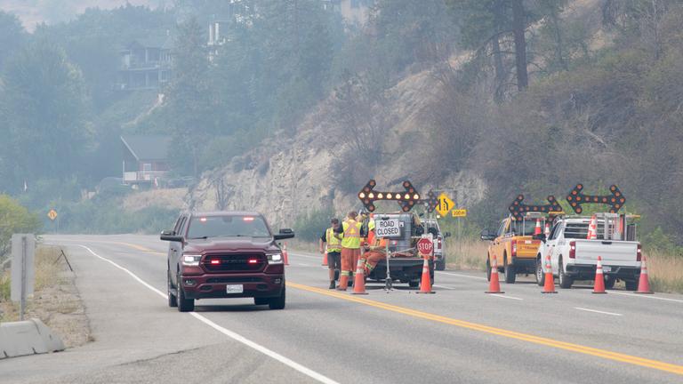 Waldbrände in British Columbia: Ein Einsatzfahrzeug fährt an einer gesperrten Strecke des Highway vorbei