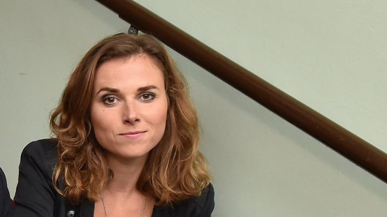 Eine junge Frau mit langen Haaren sitzt auf einer Treppe.