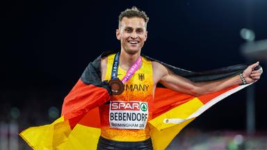 Karl Bebendorf lächelnd mit Deutschlandflagge und Bronzemedaille um den Hals