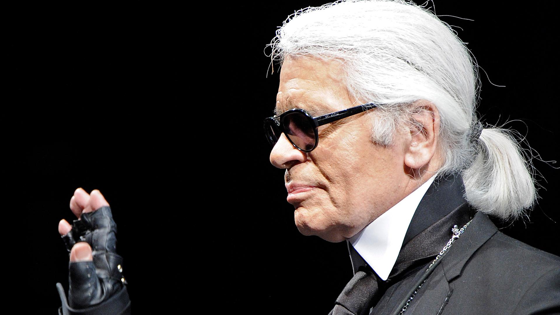 Die Umrisse von Karl Lagerfeld sind von einer blau leuchtenden Neonröhre nachgezeichnet. Das komplette Bild ist in blaues Licht getaucht.