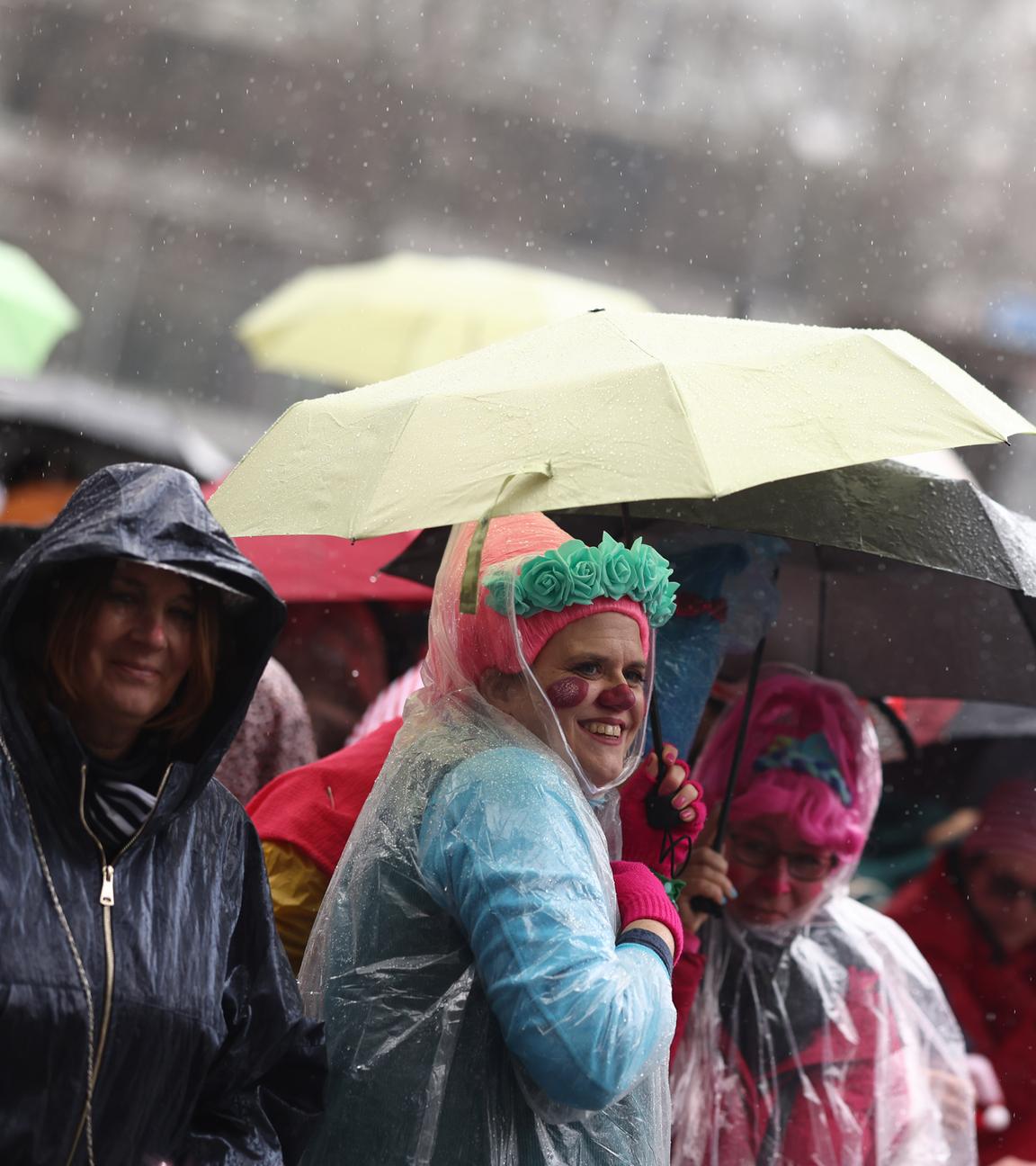 Karnevalisten schützen sich vor Regen während des Rosenmontagsumzugs in Köln.