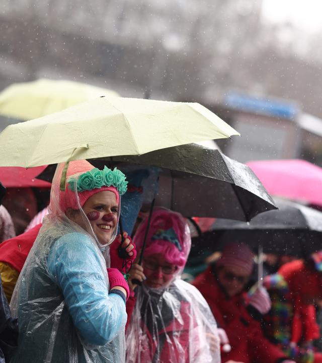 Karnevalisten schützen sich vor Regen während des Rosenmontagsumzugs in Köln.