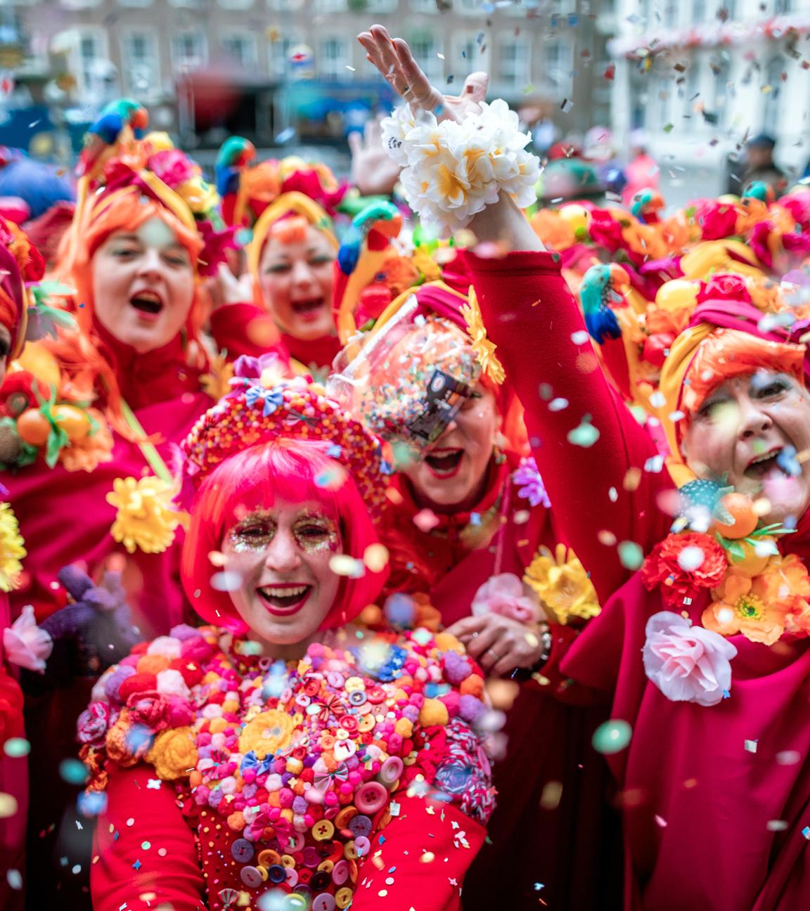 Verkleidete Frauen werfen beim Karneval in Düsseldorf mit Konfetti.
