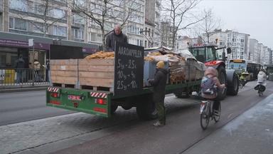 Bauer in der Stadt mit seinem Traktor, vollbeladen mit Kartoffeln, die er in Säcken verkauft