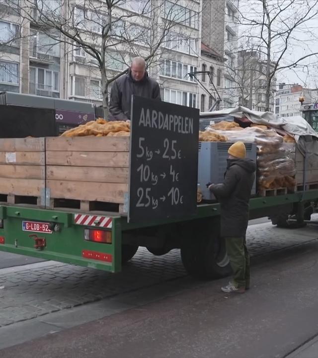 Bauer in der Stadt mit seinem Traktor, vollbeladen mit Kartoffeln, die er in Säcken verkauft