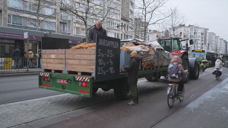 Bauer in der Stadt mit seinem Traktor, vollbeladen mit Kartoffeln, die er in Säcken verkauft