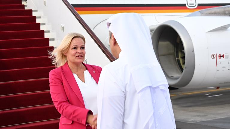 Bundesinnenministerin Nancy Faeser und der Emir von Katar schütteln sich die Hände. Im Hintergrund ein Flugzeug.