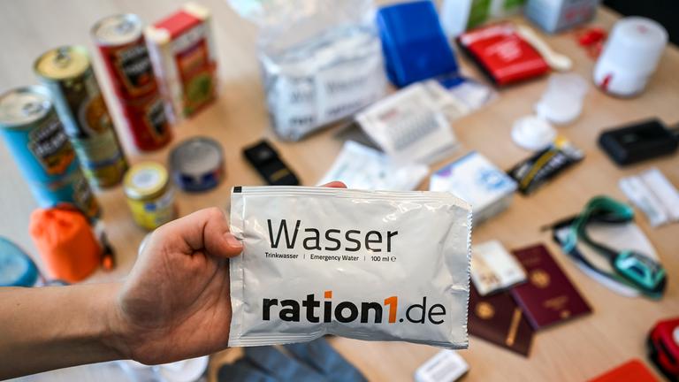 Ein Notfallpaket aus der Krisenvorsorge mit typischen Bestandteilen wie Wasser, Radio, Taschenlampe, Konserven, Erste-Hilfe-Set, Streichhölzern, Feuerzeug, Hygieneartikeln, Handschuhen...