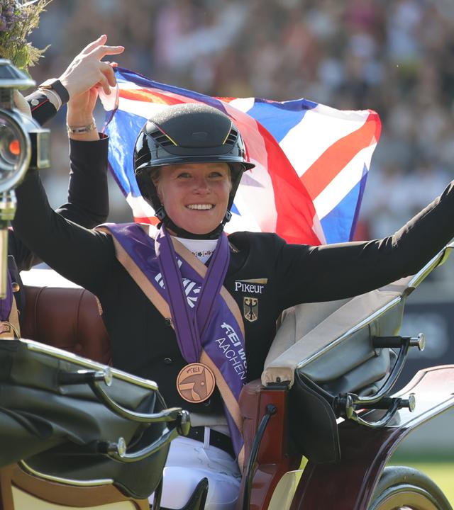Katharina Hemmer winkt aus einer Kutsche mit der Bronze Medaille um den Hals