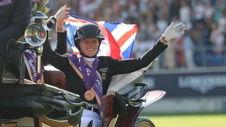 Katharina Hemmer winkt aus einer Kutsche mit der Bronze Medaille um den Hals