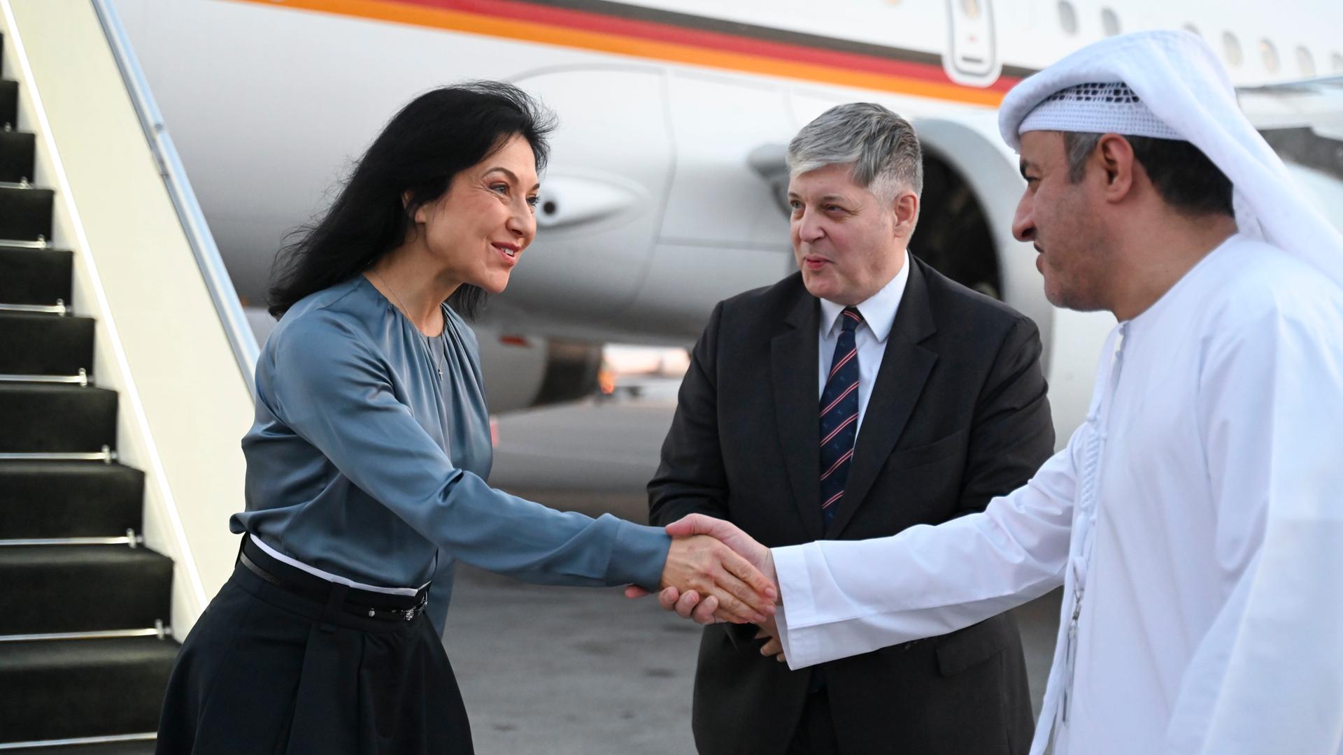 16.11.2025, Vereinigte Arabische Emirate, Abu Dhabi: Katherina Reiche (CDU), Bundesministerin für Wirtschaft und Energie, steigt in Abu Dhabi aus einem Flugzeug der Flugbereitschaft der Luftwaffe und wird von Alexander Schönfelder (M), Deutscher Botschafter in Abu Dhabi, und einem Vertreter des emiratischen Protokolls begrüßt.