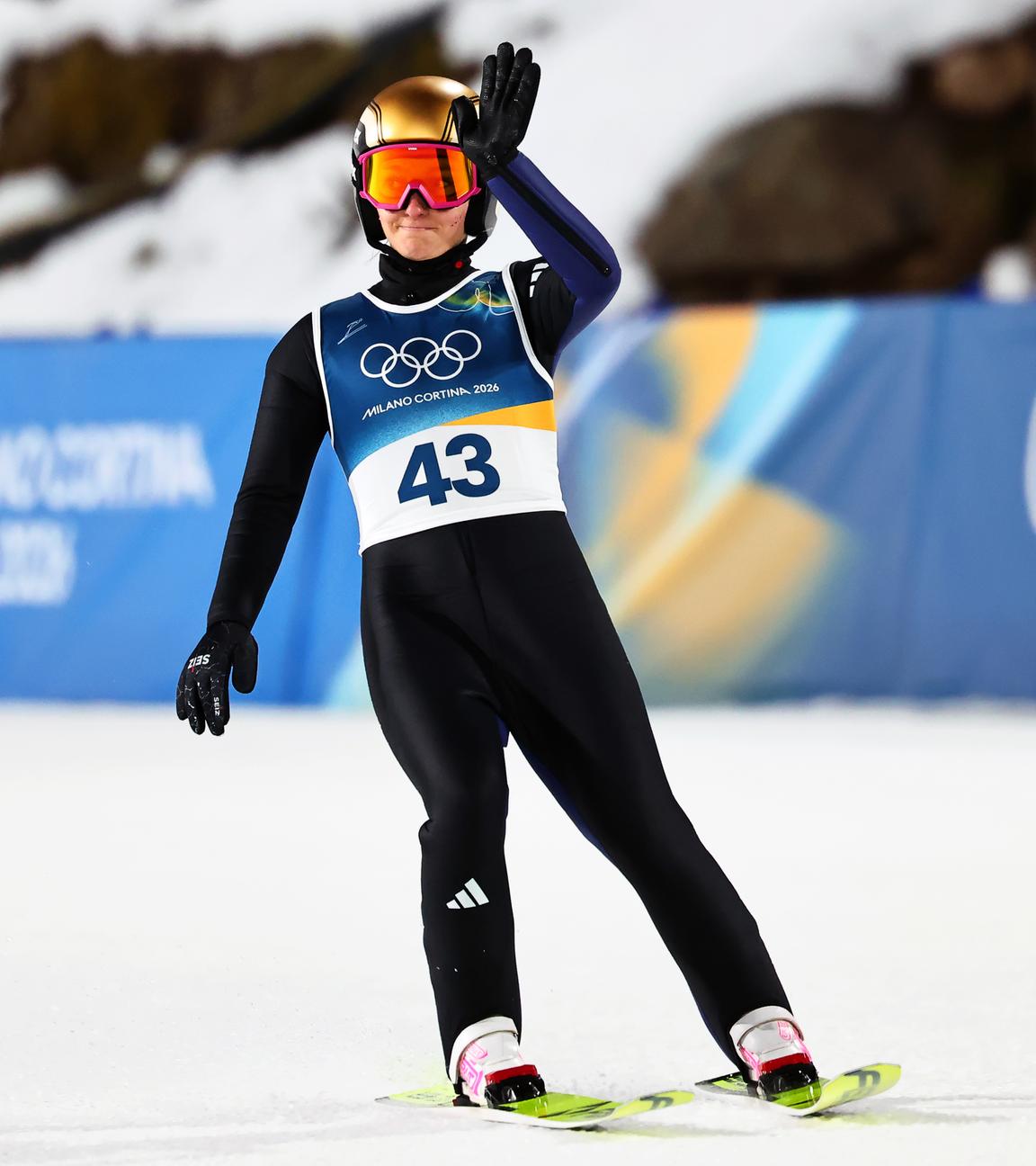 Die deutsche Skispringerin Katharina Schmid winkt nach ihrem Sprung bei den Olympischen Winterspielen 2026 in Cortina den Zuschauern zu