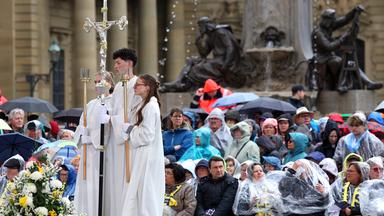 Besucher des Katholikentags nehmen am 14.05.2026 an einem Gottesdienst auf dem Residenzplatz in Würzburg teil.