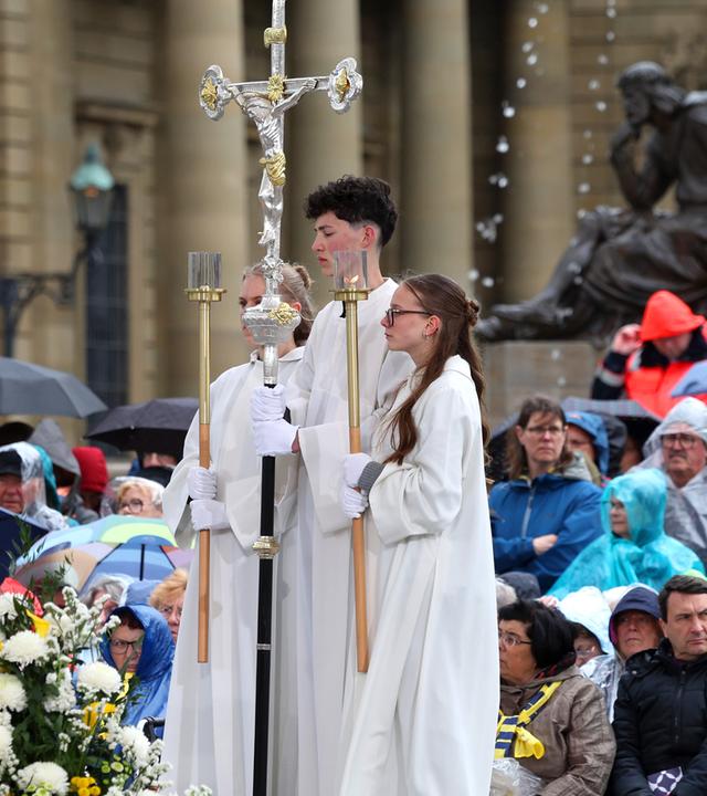 Besucher des Katholikentags nehmen am 14.05.2026 an einem Gottesdienst auf dem Residenzplatz in Würzburg teil.