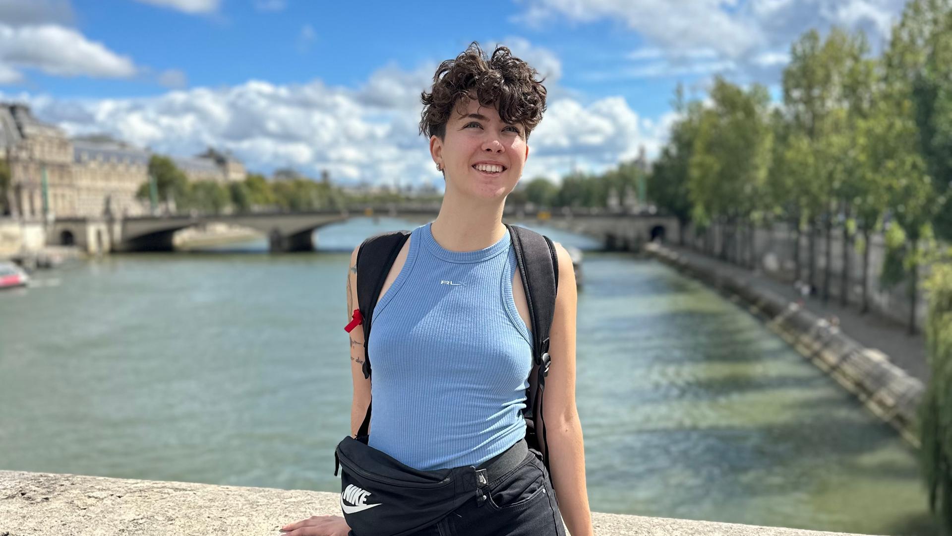 Kathy Peters steht an einer Brücke in der Sonne.