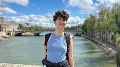 Kathy Peters steht an einer Brücke in der Sonne.