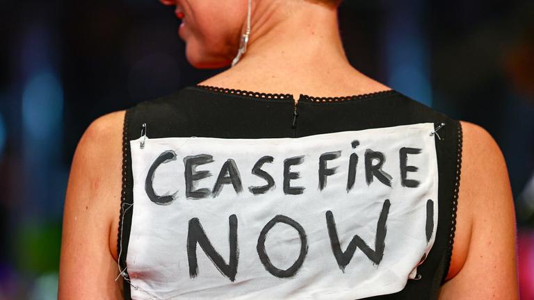 Katrin Pors posiert vor der Eröffnungsfeier der 74. Internationalen Filmfestspiele Berlin "Berlinale" am 15.02.2024 in Berlin mit einem Banner auf dem Rücken, auf dem "Ceasefire now" steht.