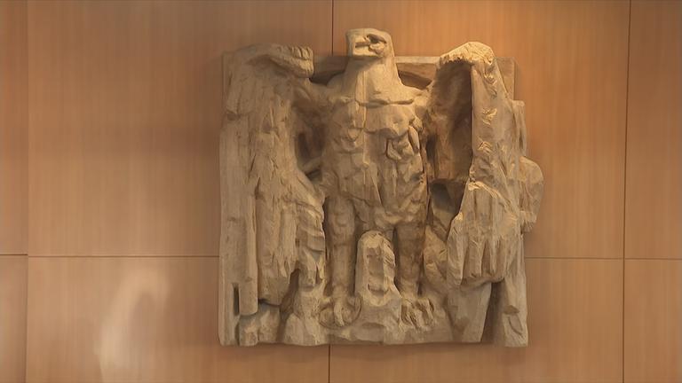 Auf dem Bild sieht man ein Monument an der Wand mit einem Adler.