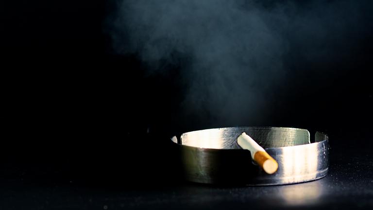 Auf dem Foto ist ein Aschenbecher mit einer Zigarette zu sehen. 