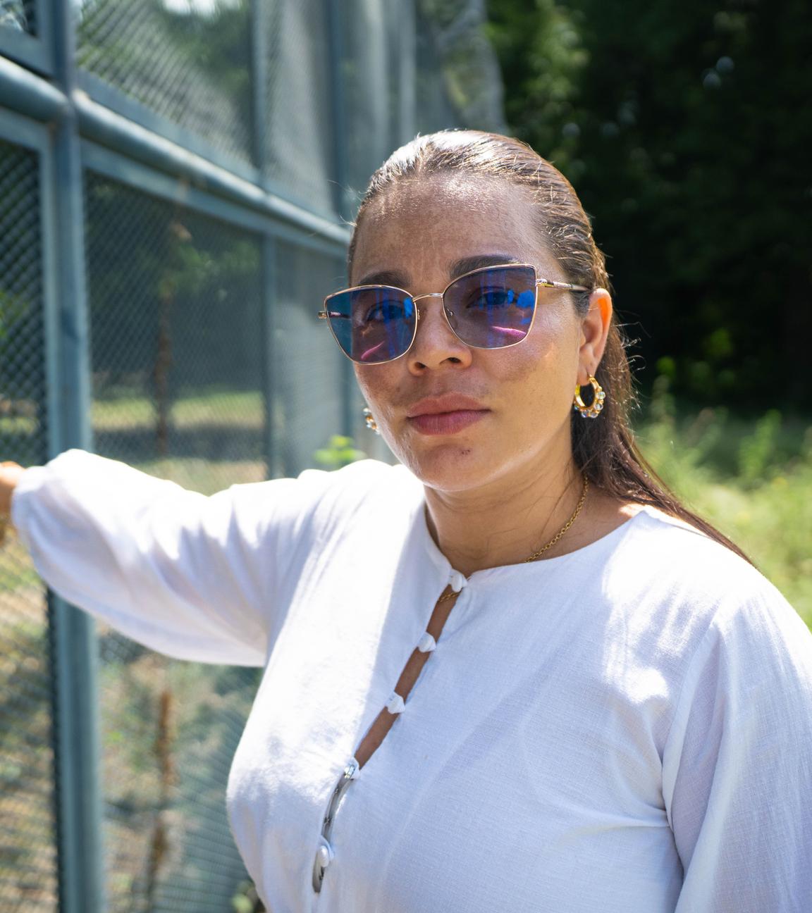 Kelly Diaz aus Kolumbien steht an einem Gefängniszaun.