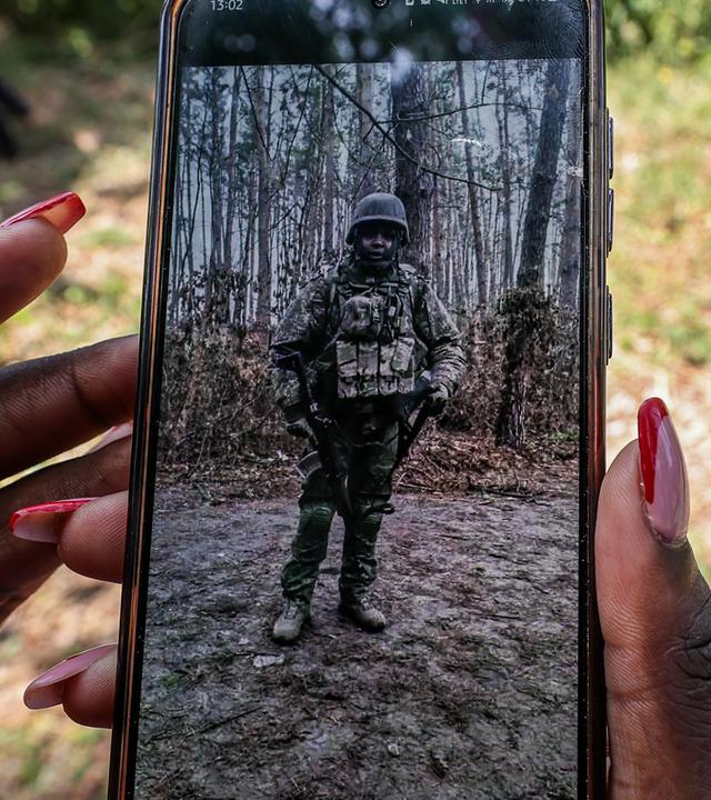 Ein Angehöriger des in Russland gefallenen Charles Waithaka Wangari (31) zeigt bei einer symbolischen Trauerfeier in Mukurwe-ini, Kenia, ein Foto des Verstorbenen in Militäruniform.