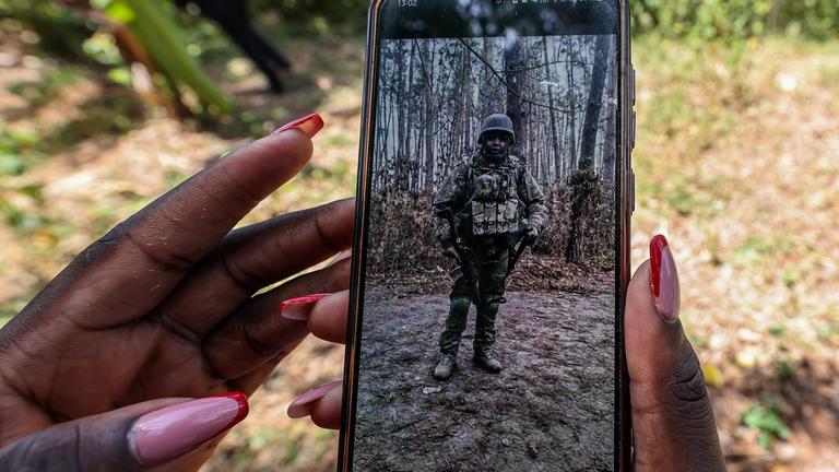 Ein Angehöriger des in Russland gefallenen Charles Waithaka Wangari (31) zeigt bei einer symbolischen Trauerfeier in Mukurwe-ini, Kenia, ein Foto des Verstorbenen in Militäruniform.