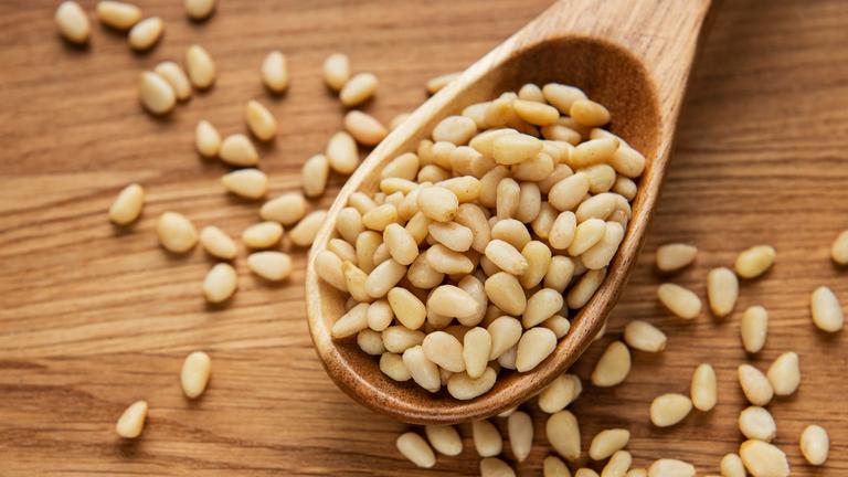 Pinienkerne auf einem Holzlöffel