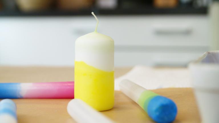Eine Kerze ist oben weiß und unten gelb. Sie wurde mit einfachen Tricks verschönert.