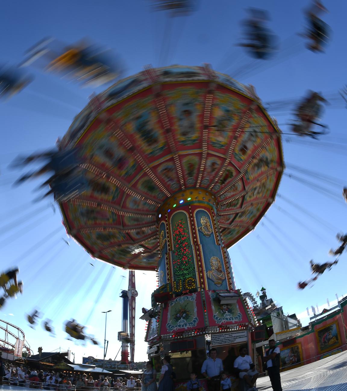 Fahrendes Kettenkarusell auf der Münchner Wiesn bei blauem Himmel.