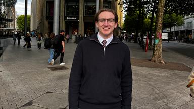 Kevin steht in einer Einkaufsstraße in Hamburg.